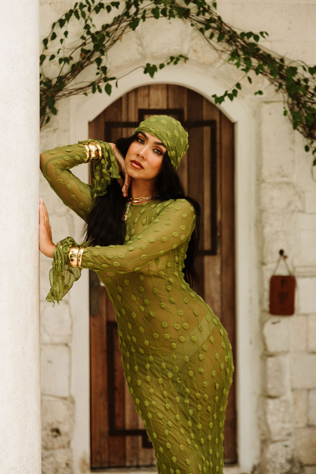 The Capri Dress in Positano Olive, framed by a whitewashed archway.