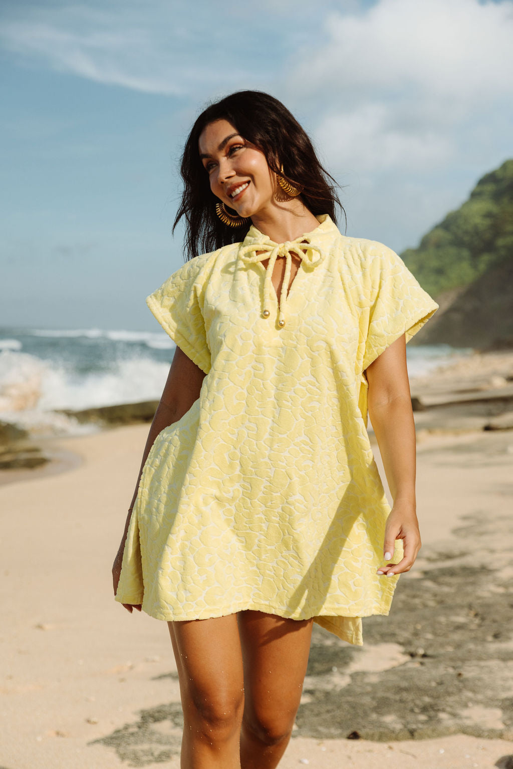 The Mila Poncho in Butter Yellow, at the water's edge.
